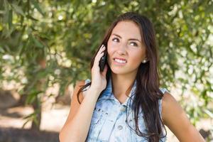 mujer joven de raza mixta infeliz y confundida hablando por teléfono celular afuera foto