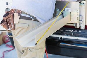 Worker Measuring Rain Gutter Processing Through Seamless Shaping Machine photo