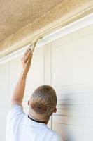 Professional Painter Cutting In With Brush to Paint Garage Door Frame photo