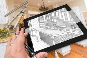 Hand on Computer Tablet Showing Drawing of Kitchen Photo Behind with Compass and Ruler