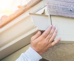 Worker Attaching Aluminum Rain Gutter to Fascia of House. photo