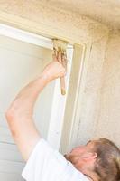 Professional Painter Cutting In With Brush to Paint Garage Door Frame photo