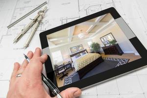 Hand of Architect on Computer Tablet Showing Bedroom Over House Plans photo