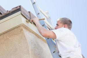 Professional Painter Using A Brush to Paint House Fascia photo