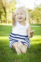 Cute Little Girl Sitting and Laughing in the Grass photo
