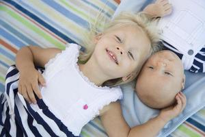 Little Sister Laying Next to Her Baby Brother on Blanket photo