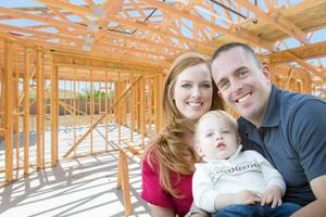 joven familia militar dentro del marco de su nuevo hogar en el sitio de construcción. foto