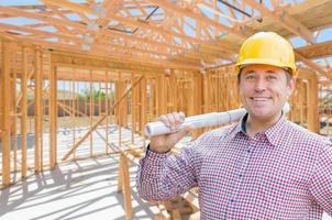 Contractor With Plans On Site Inside New Home Construction Framing. photo