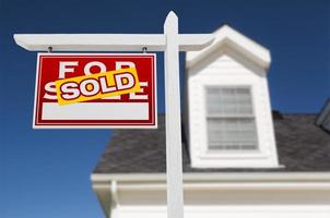 Left Facing Sold For Sale Real Estate Sign In Front of House and Deep Blue Sky. photo