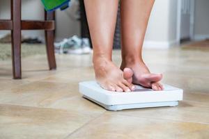 Woman Standing on Scale At Home Reluctantly Viewing Weight photo