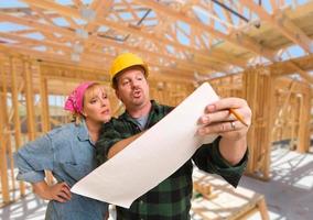 Contractor Showing Plans to Woman On Site Inside New Home Construction Framing. photo