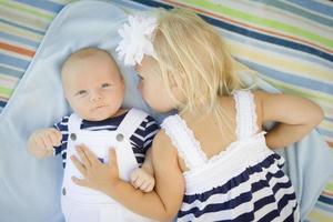 Little Sister Laying Next to Her Baby Brother on Blanket photo