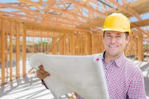 Contractor With Plans On Site Inside New Home Construction Framing. photo