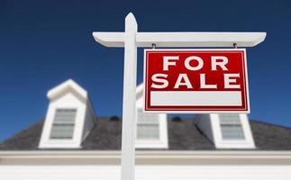 Right Facing For Sale Real Estate Sign In Front of House and Deep Blue Sky. photo