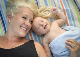 niño pequeño envuelto en su manta descansando con mamá foto