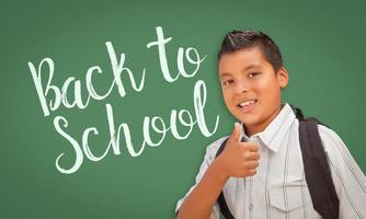 pulgar arriba niño hispano frente a la pizarra de regreso a la escuela foto