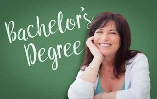 Bachelor's Degree Written On Green Chalkboard Behind Smiling Middle Aged Woman photo