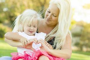 niña con madre haciendo forma de corazón con las manos foto