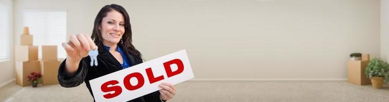 Banner of Hispanic Woman Inside Room with Boxes Holding House Keys and Sold For Sale Real Estate Sign. photo