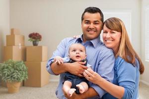 Mixed Race Family with Baby in Room with Packed Moving Boxes photo