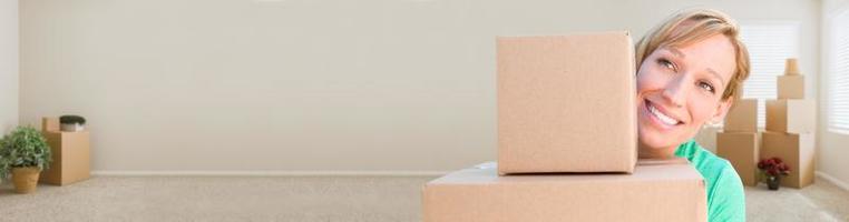 Banner of Happy Young Adult Woman Holding Moving Boxes In Empty Room In A New House. photo