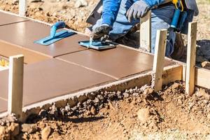 trabajador de la construcción usando una ranuradora manual en cemento húmedo formando una nueva piscina foto