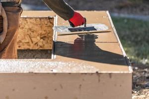 Construction Worker Using Trowel On Wet Cement Forming Coping Around New Pool photo