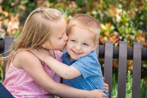 hermana joven y hermano divirtiéndose en el banco en el parque foto