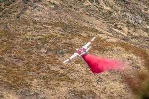 Winchester, CA USA - June 14, 2020 Cal Fire aircraft drops fire retardant on a dry hilltop wildfire near Winchester, California. photo