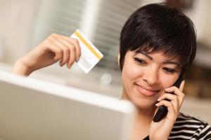 Multiethnic Woman Holding Phone and Credit Card Using Laptop photo