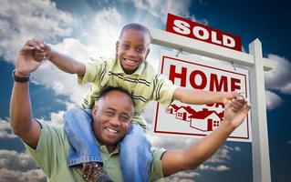 African American Father with Son In Front of Sold Home For Sale Real Estate Sign photo