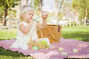 Cute Baby Girl colorear huevos de Pascua en manta para picnic foto