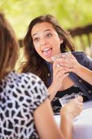 Expressive Young Adult Woman Having Drinks and Talking with Her Friend Outdoors photo