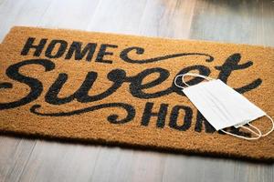 Medical Face Masks Rests on Home Sweet Home Welcome Mat Amidst The Coronavirus Pandemic photo