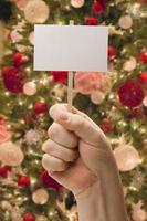 Hand Holding Blank Card In Front of Decorated Christmas Tree. photo