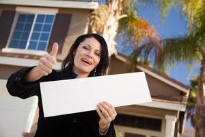 Attractive Hispanic Woman Holding Blank Sign in Front of House photo