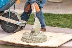 trabajador de la construcción colocando cemento húmedo a bordo en el sitio de construcción de la piscina foto