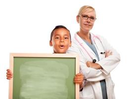 doctora con niño hispano sosteniendo pizarra foto