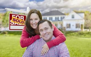 Couple In Front of Sold For Sale Sign and House photo