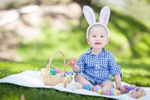 Mixed Race Chinese and Caucasian Baby Boy Outside Wearing Rabbit Ears Playing with Easter Eggs photo