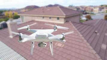 Unmanned Aircraft System UAV Quadcopter Drone In The Air Over House Inspecting the Roof photo