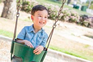 Chinese and Caucasian Boy Having Fun On The Swings At Playground. photo