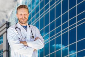 Handsome Young Adult Male Doctor With Beard In Front of Hospital Building photo