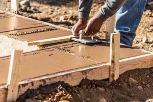 trabajador de la construcción usando una ranuradora manual en cemento húmedo formando una nueva piscina foto