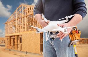 trabajador de la construcción y piloto de drones con cinturón de herramientas sosteniendo drones en el sitio de construcción foto