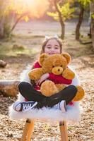 Cute Young Mixed Race Girl Hugging Teddy Bear Outdoors photo