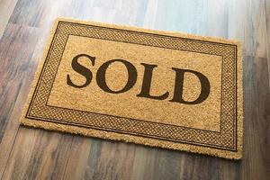 Sold Welcome Mat On A Wood Floor Background photo