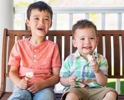 jóvenes hermanos chinos y caucásicos de raza mixta disfrutando de sus conos de helado foto