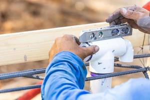 fontanero usando nivel mientras instala tubería de pvc en el sitio de construcción foto