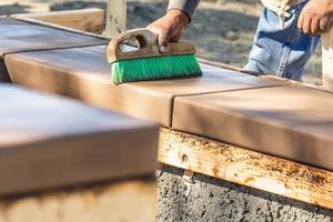 trabajador de la construcción usando cepillo en cemento húmedo formando afrontamiento alrededor de la nueva piscina foto